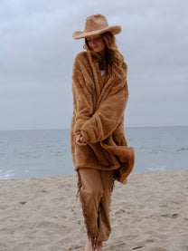 Model wearing the Camel Brown Long Papàsweater with a tan hat on the beach