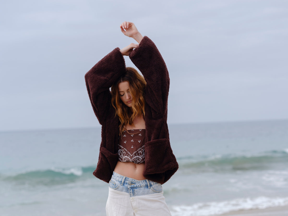 Model wearing the Dark Chocolate Crop Papàsweater on the beach
