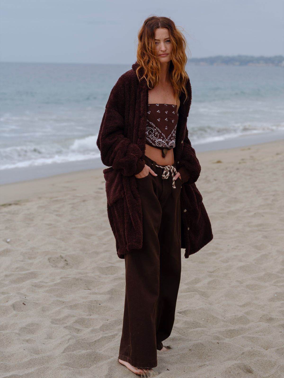 Model wearing the Dark Chocolate Long Papàsweater on the beach